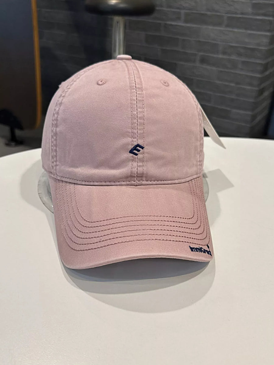 Pink baseball cap with a logo on a white surface