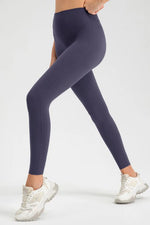 Person wearing dark purple leggings and white sneakers on a light gray background