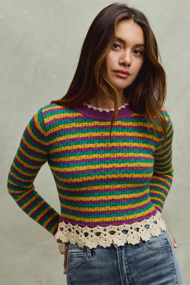 Woman wearing a colorful striped sweater with a plain background