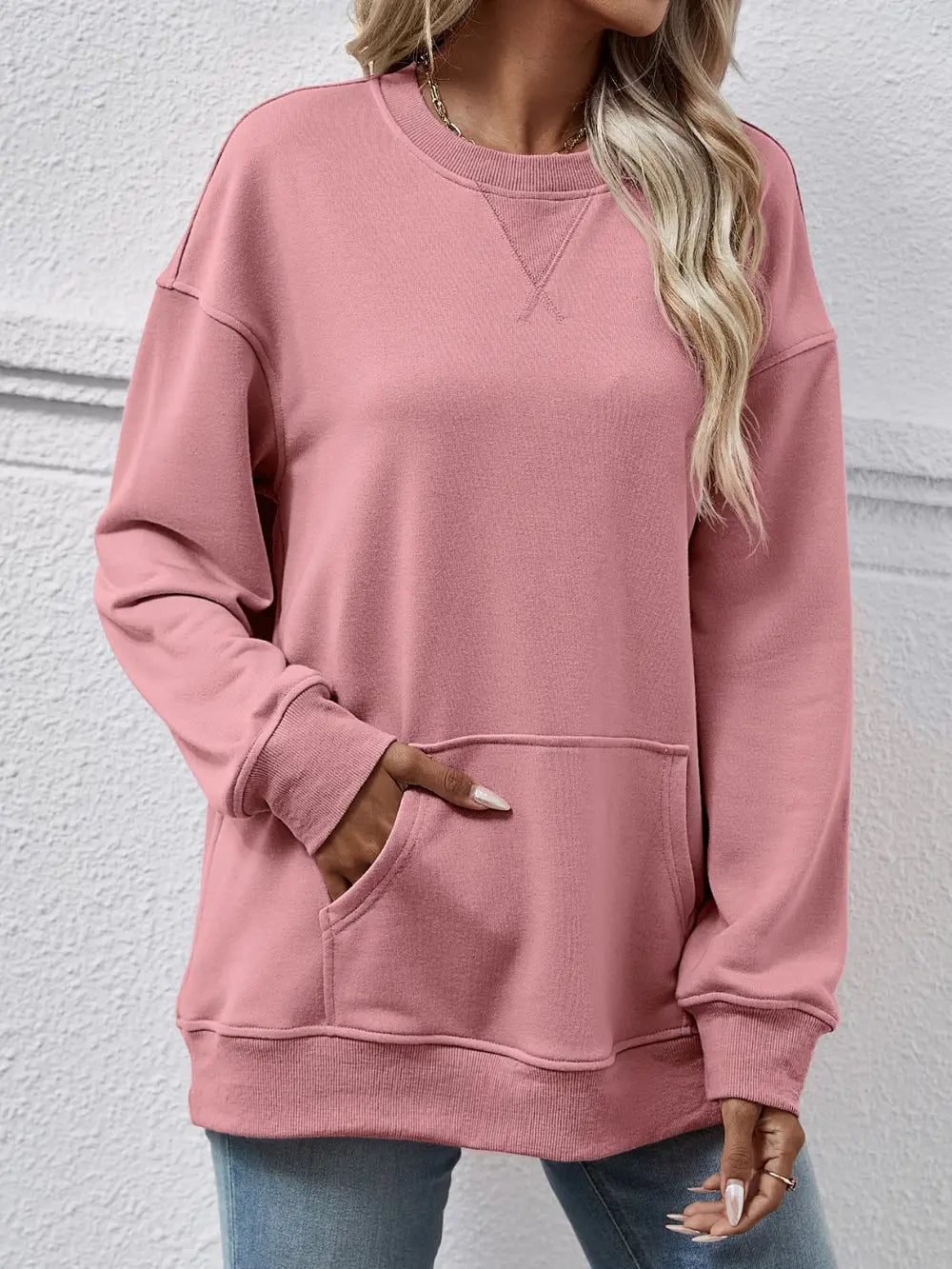 Person wearing a pink sweatshirt with a plain background