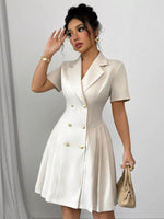 Woman wearing a white dress with gold buttons against a plain background