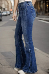 Person wearing blue flared jeans on a city street.