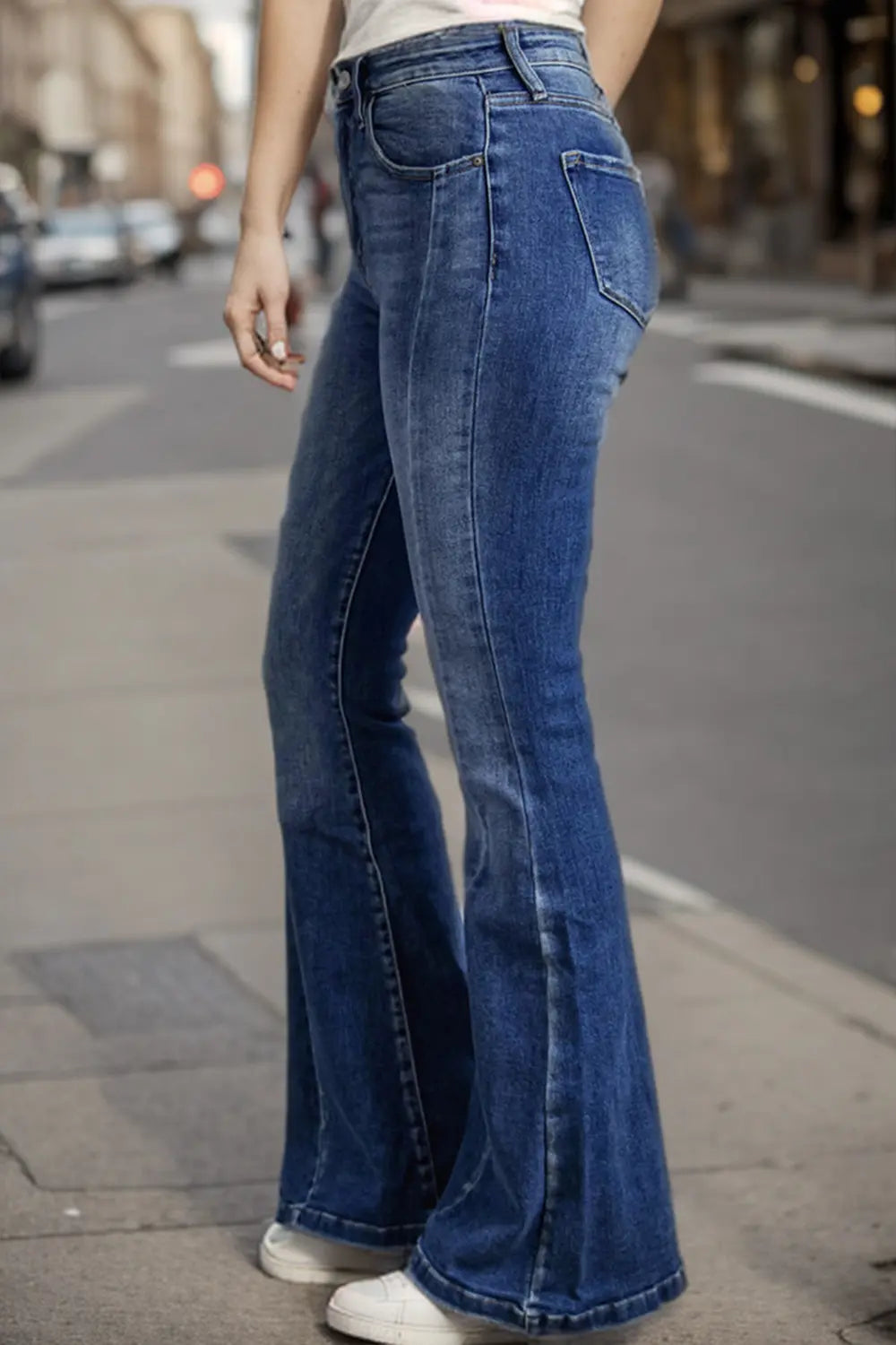 Person wearing blue flared jeans on a city street.