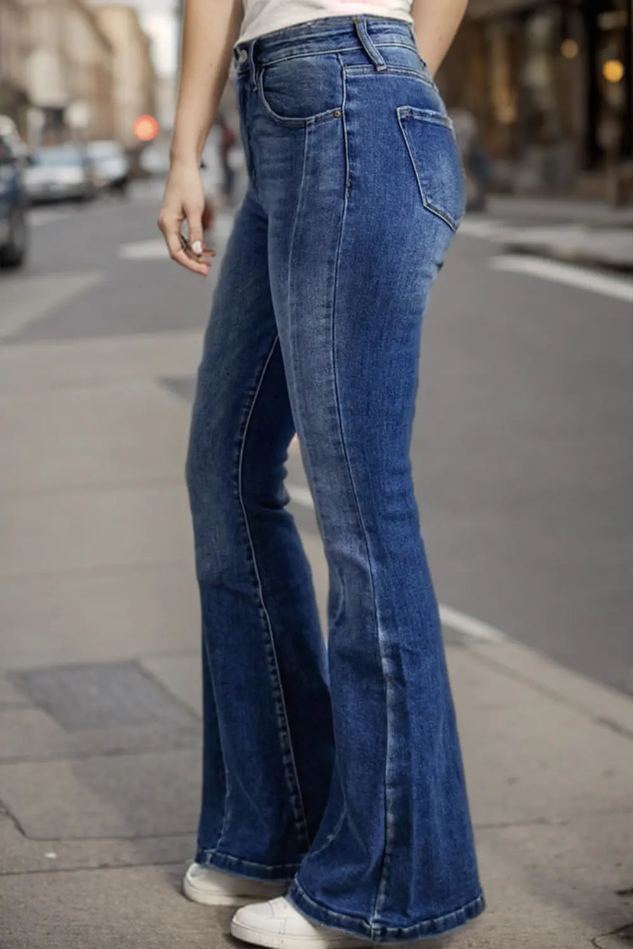 Person wearing blue flared jeans on a city street.