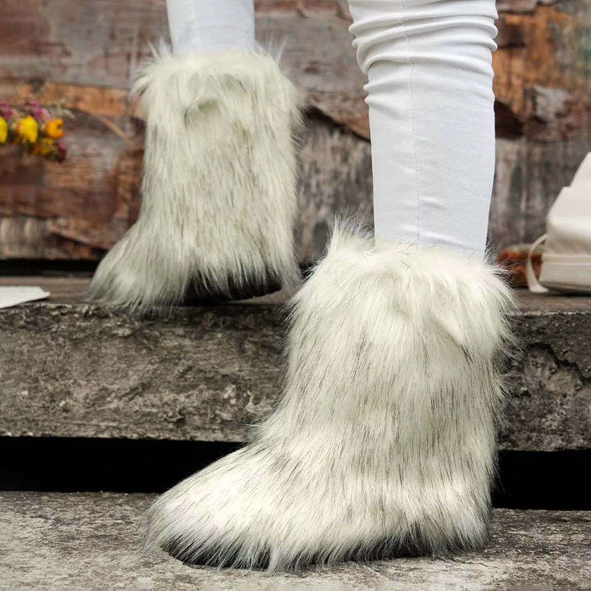 White furry boots worn with white leggings on a stone step.