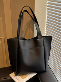 Black leather tote bag on a surface with a window in the background