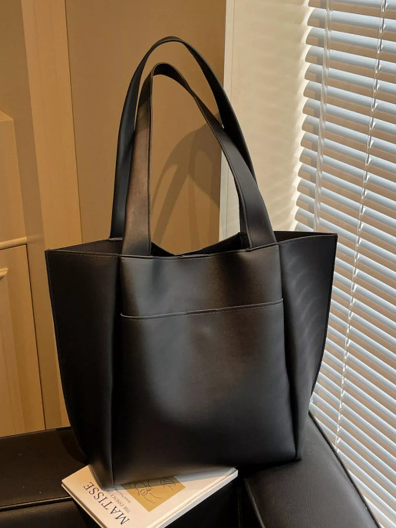 Black leather tote bag on a surface with a window in the background