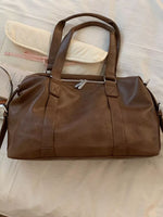 Brown leather duffel bag on a light-colored surface