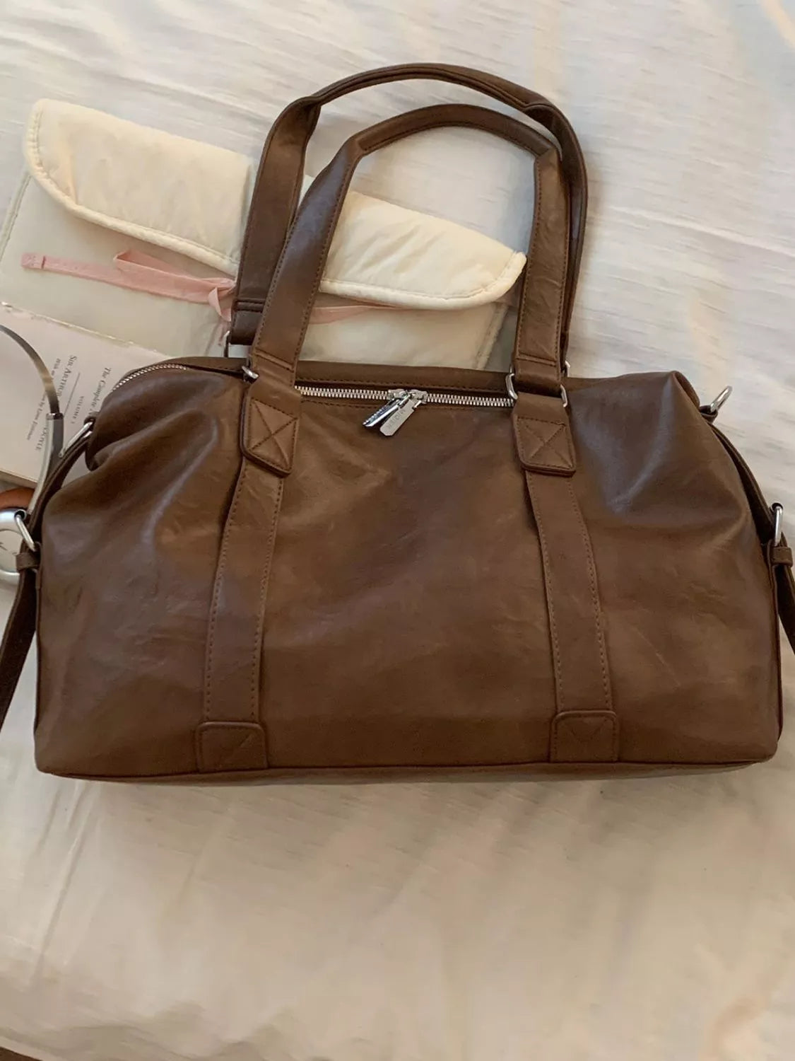 Brown leather duffel bag on a light-colored surface