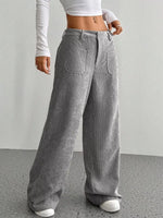 Person wearing gray corduroy pants with a white top against a plain background