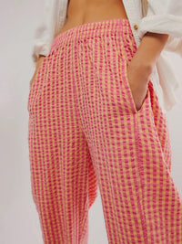 Person wearing pink and yellow checkered pants with a white background