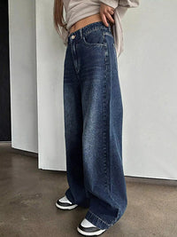 Person wearing wide-leg jeans and sneakers in a minimal indoor setting