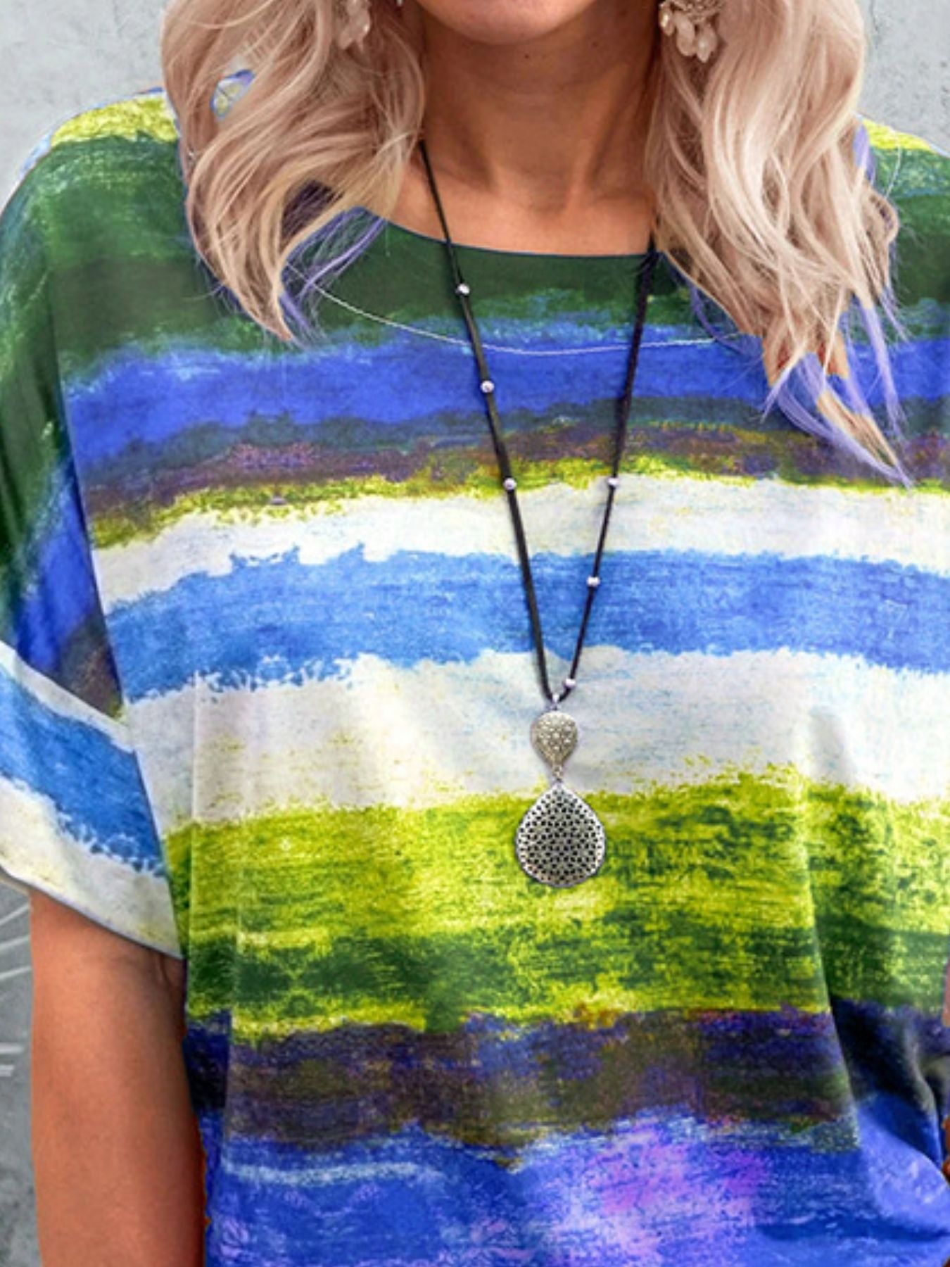 Person wearing a colorful striped shirt with a necklace