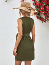 Woman wearing an olive green dress and a wide-brimmed hat with a floral wreath in the background.