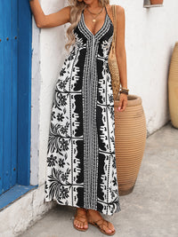 Woman wearing a black and white patterned dress standing against a white wall with a blue door.