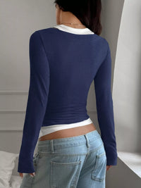 Person wearing a blue long-sleeve top and light blue jeans in a neutral setting