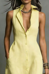 Woman wearing a light yellow sleeveless dress with a plunging neckline against a gray background