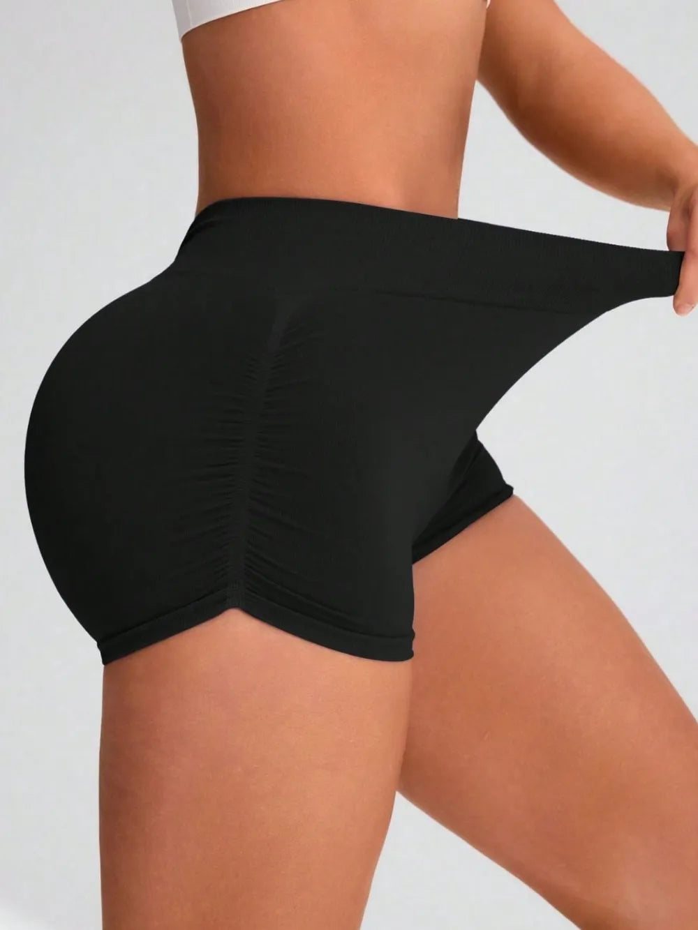 Black athletic shorts worn by a person on a light gray background