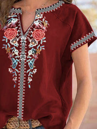 Red embroidered top with floral patterns on a blurred background