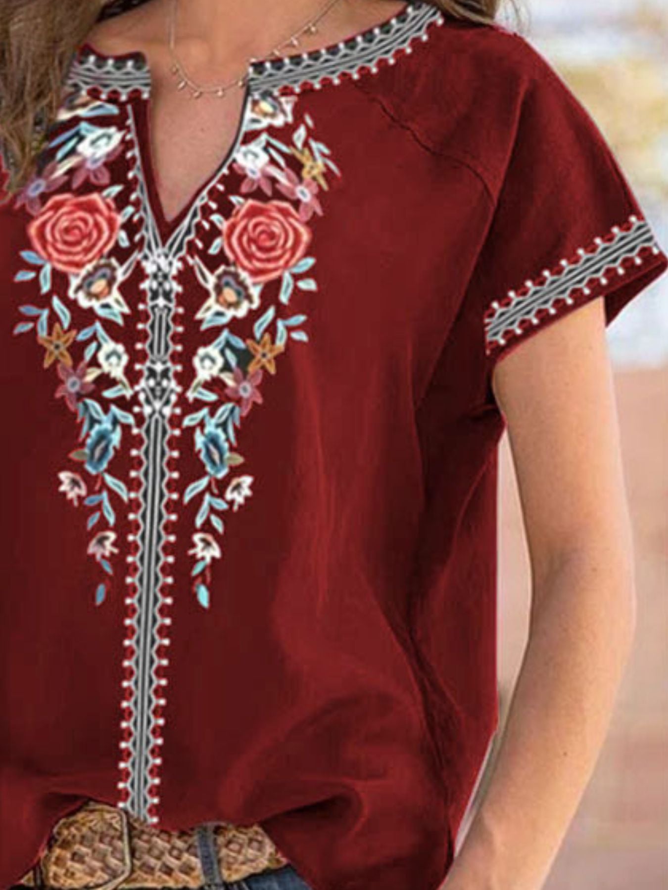 Red embroidered top with floral patterns on a blurred background