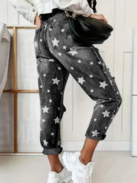 Person wearing star-patterned jeans with a black waist bag indoors.