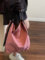 Person holding a pink handbag indoors on a wooden floor.