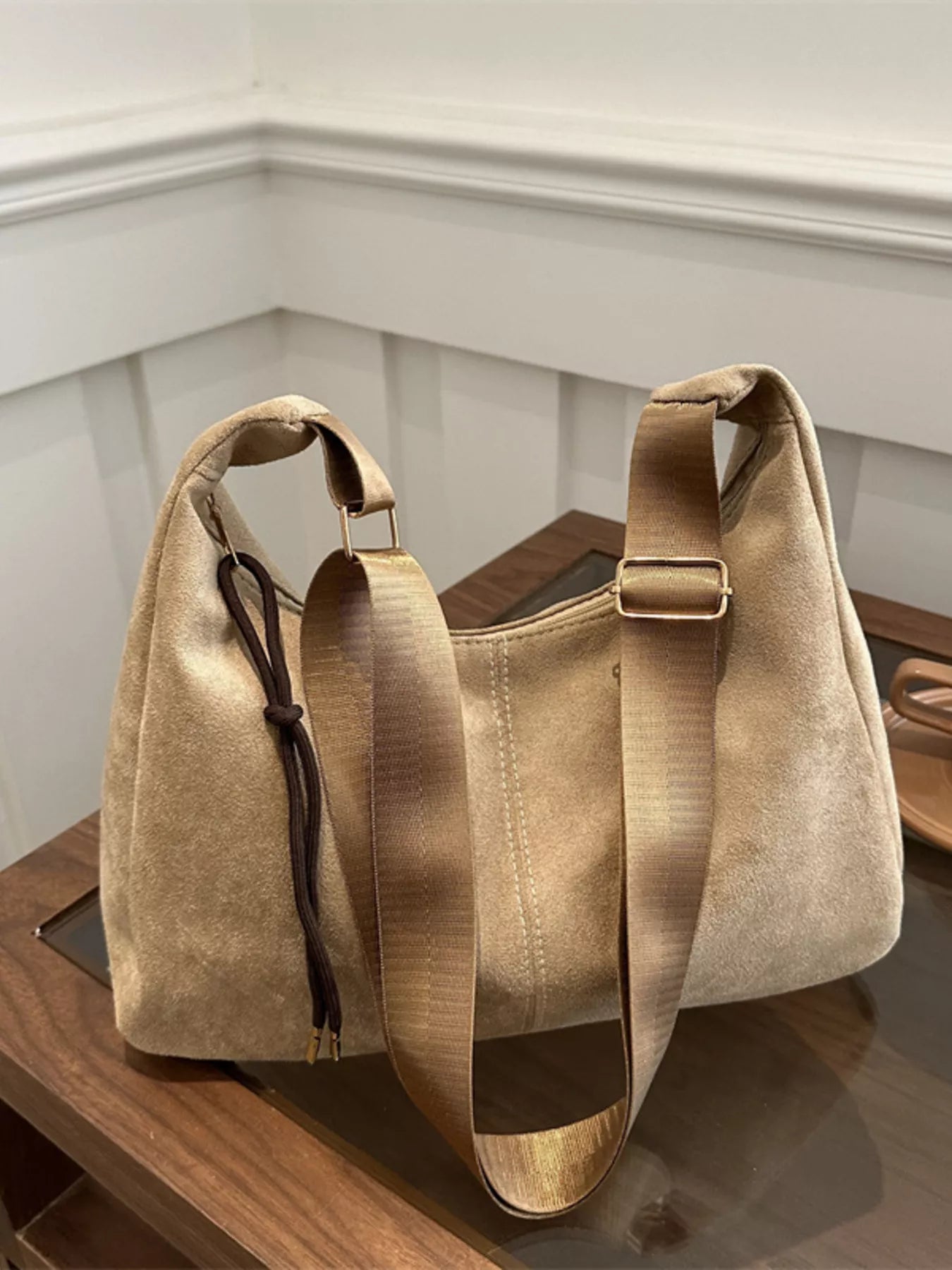 Beige handbag with a strap on a wooden surface