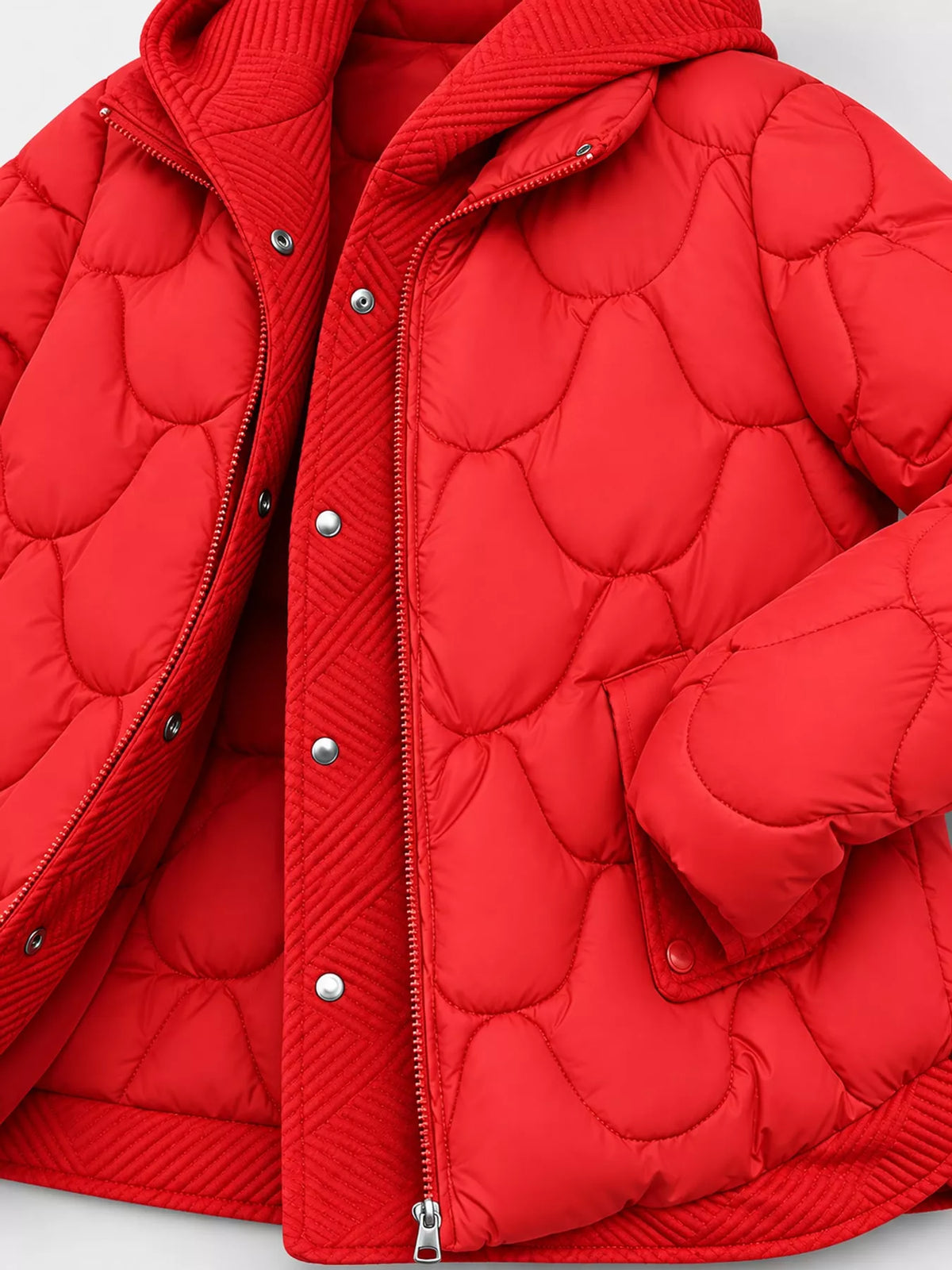 A close-up of a bright red quilted puffer jacket with a hood, featuring a central zipper and silver snap-button closure on a light gray background.