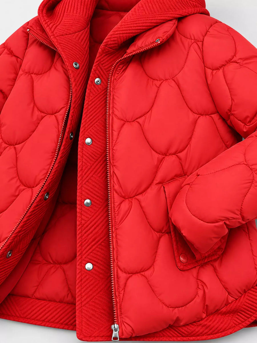 A close-up of a bright red quilted puffer jacket with a hood, featuring a central zipper and silver snap-button closure on a light gray background.