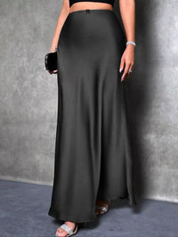 Person wearing a long black skirt against a gray background