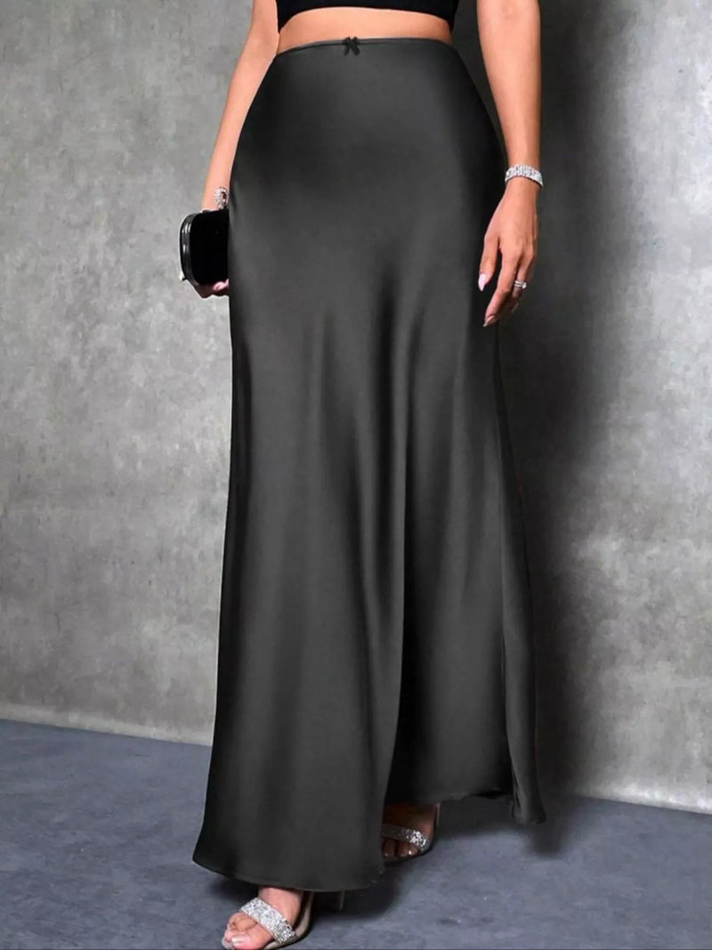 Person wearing a long black skirt against a gray background