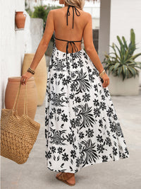 Woman wearing a black and white floral dress holding a woven bag outdoors.