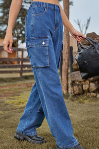 Person wearing blue jeans holding a black bag outdoors.
