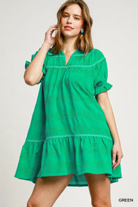 Woman wearing a green dress with lace details on a plain background