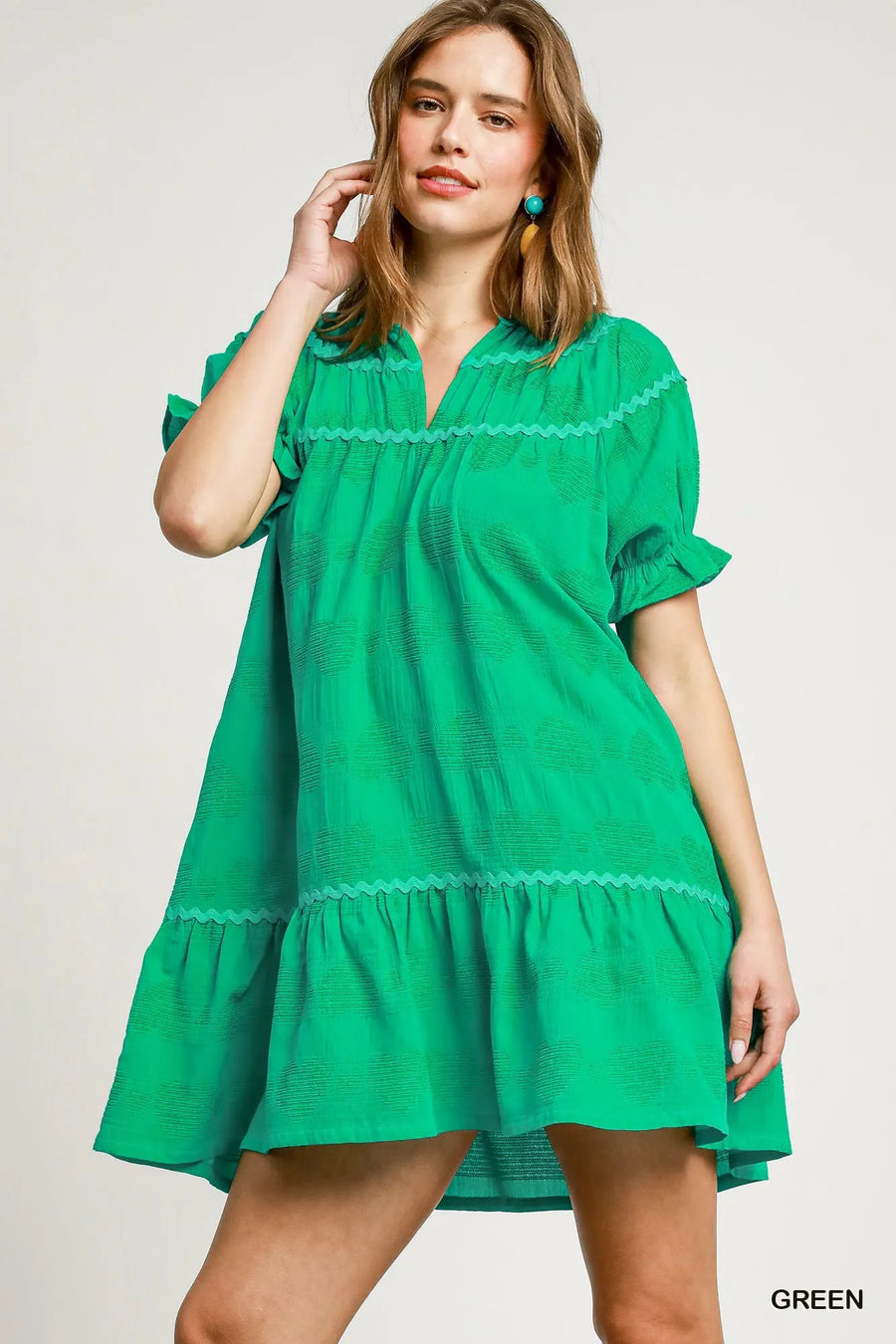 Woman wearing a green dress with lace details on a plain background