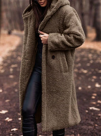 Person wearing a long brown coat in a forest setting