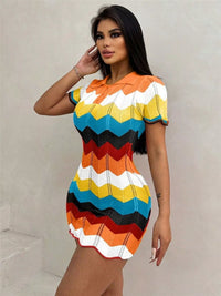 Woman wearing a colorful striped dress against a plain background