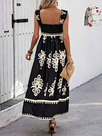 Woman wearing a black dress with white embroidery walking on a street.