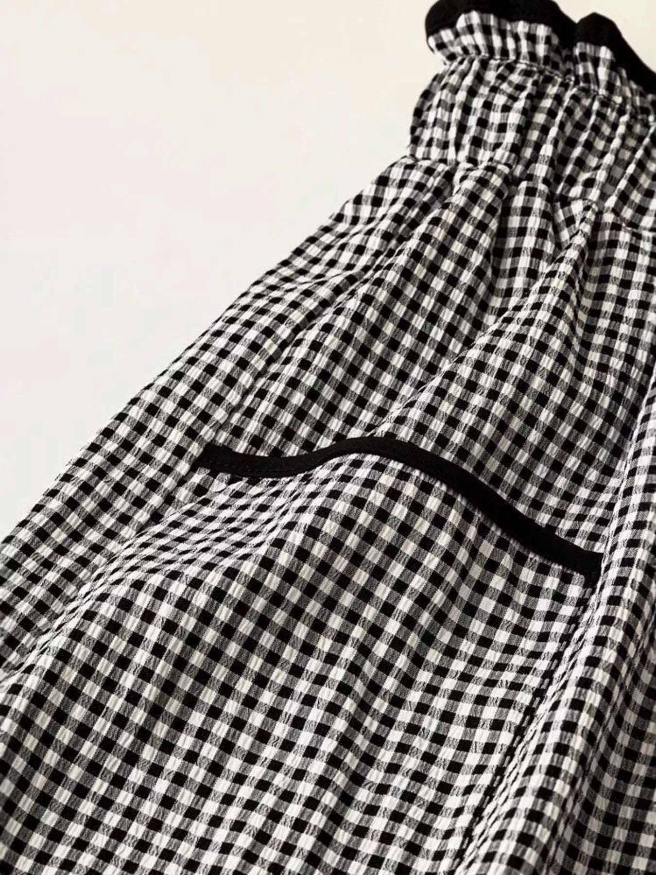 Black and white checkered pants with a black waistband on a light background