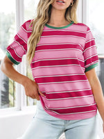 Woman wearing a pink and red striped shirt with green trim indoors.