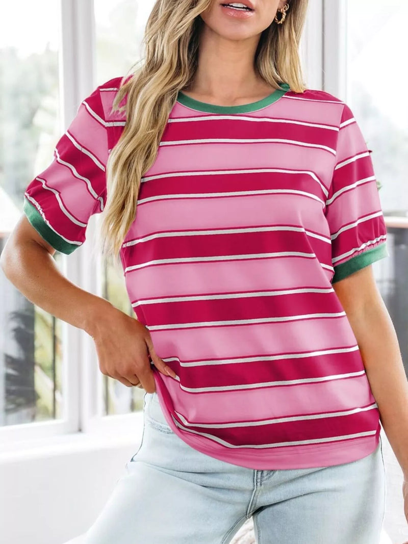 Woman wearing a pink and red striped shirt with green trim indoors.