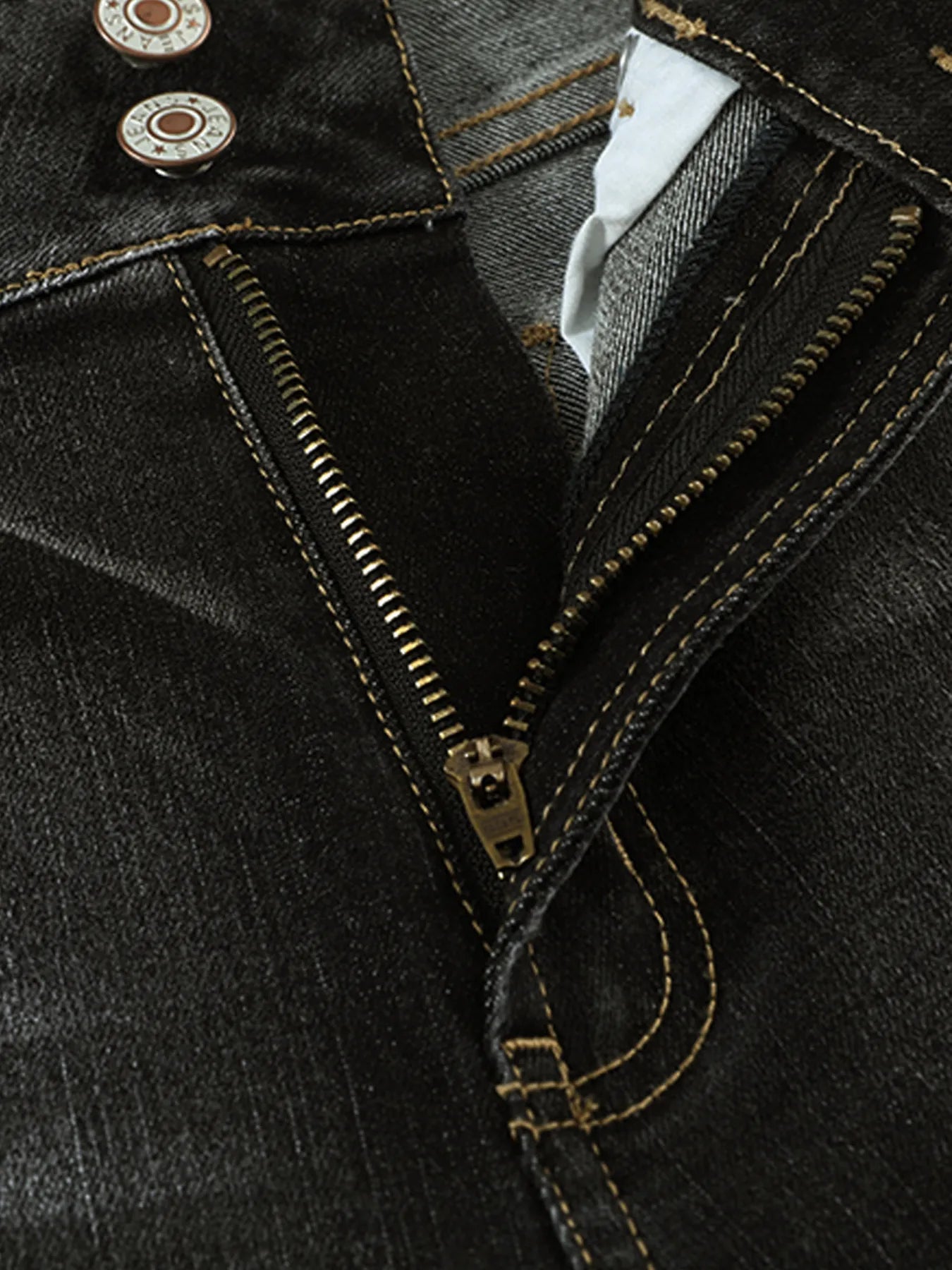 Close-up of a black denim jacket with gold zipper and buttons.