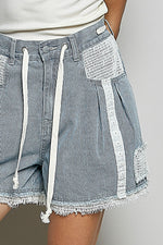 Close-up of blue and white striped shorts with lace detailing on a neutral background