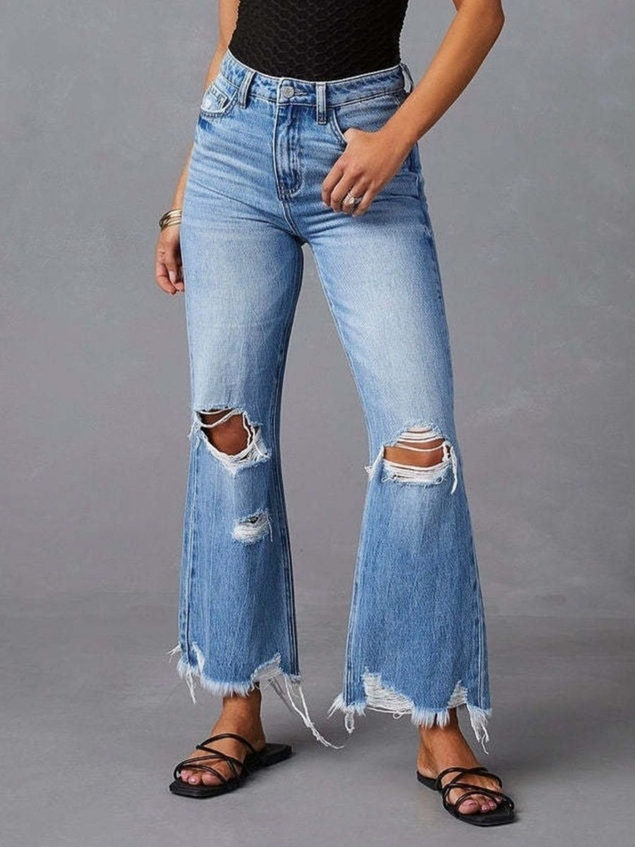 Person wearing ripped blue jeans on a gray background