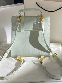 Light blue handbag with gold accents on a white surface