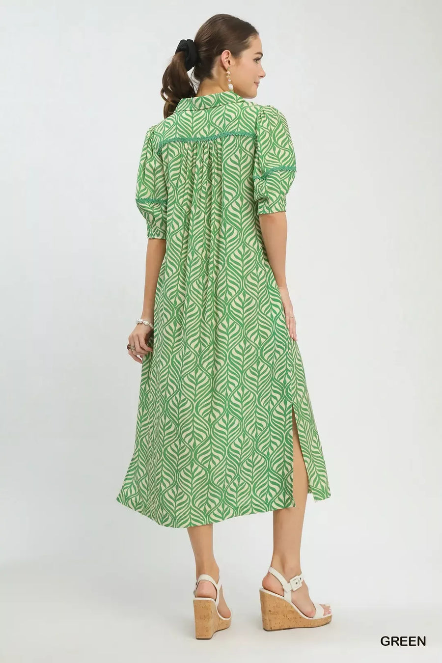 Woman wearing a green patterned dress on a white background