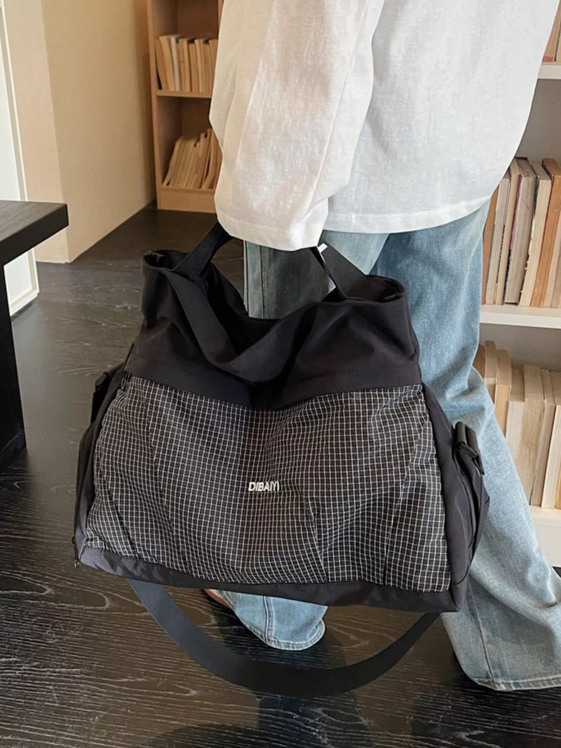 Person holding a black and gray checkered bag indoors