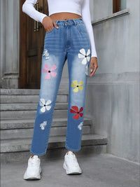 Person wearing blue jeans with colorful floral patches on a concrete staircase.