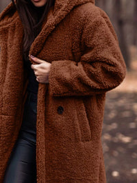 Person wearing a brown teddy coat with a blurred background