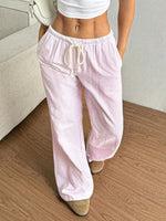 Person wearing light pink striped pants with a white top on a wooden floor.